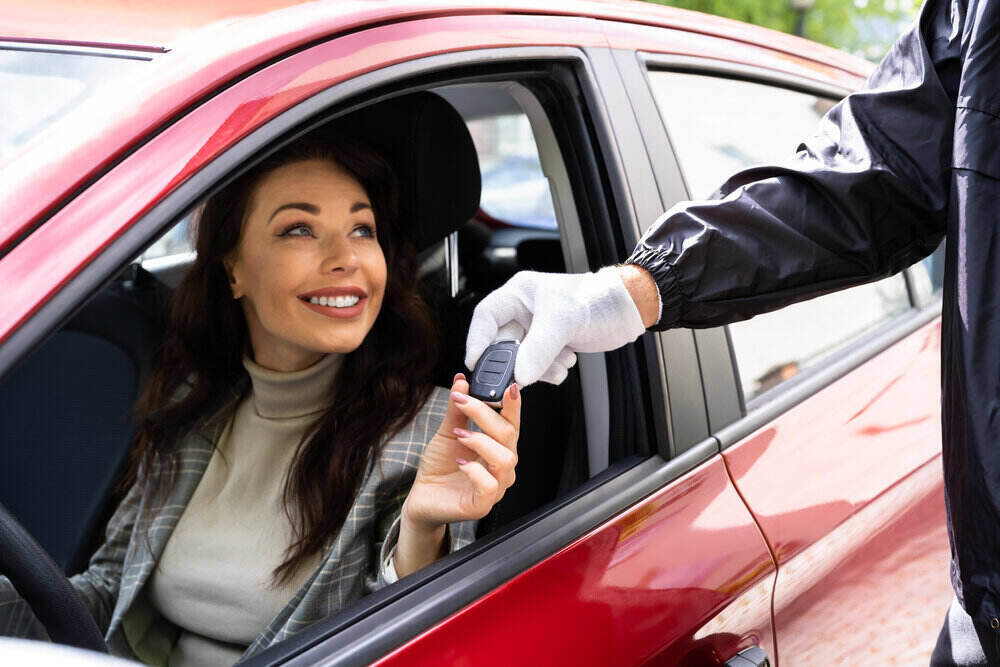 araç kiralama vale hizmeti, kırmızı arabada araç anahtarını teslim alan kadın sürücü