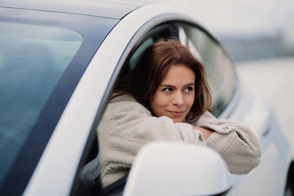 günlük araba kiralama fiyatları ne kadar? kadın sürücü araç kapısından dışarı bakıyor
