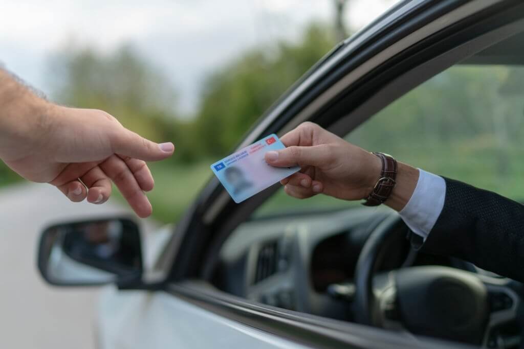 ehliyet yenileme nasıl yapılır? araba camından sürücü belgesini uzatan el