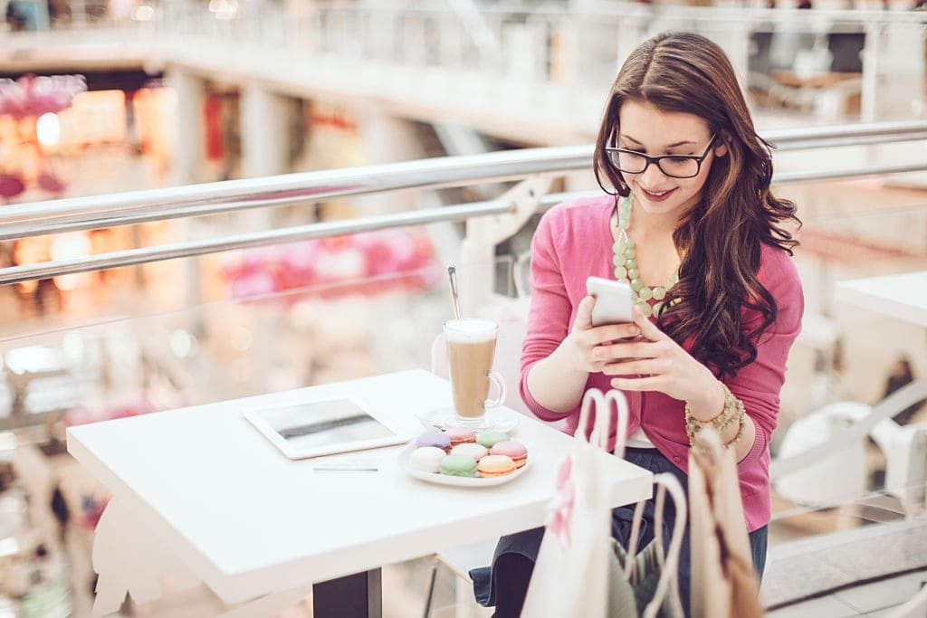 alışveriş merkezinde telefonuna bakan mutlu genç kadın, trabzon alışveriş merkezleri
